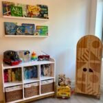 Bright nursery furniture with a wooden bookshelf beside a wardrobe for infant clothing.